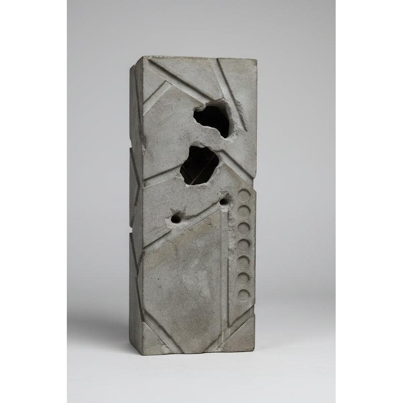 Decorative stone with geometric patterns and circular holes on a blurred natural background